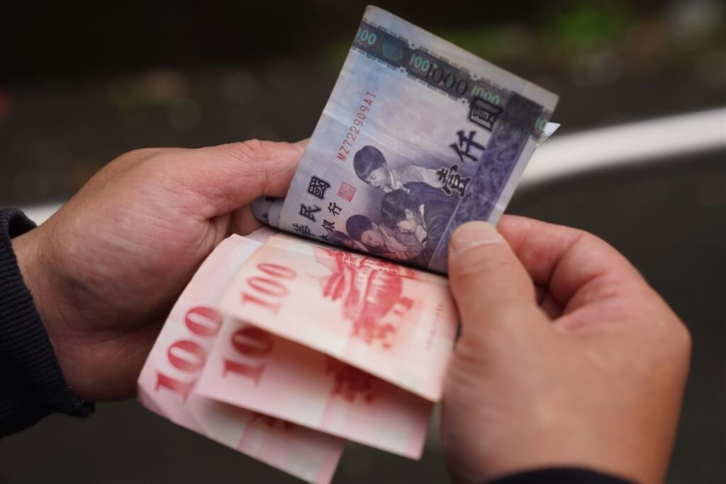 Foto Seorang pria menghitung uang kertas NTD. (Foto CNA)