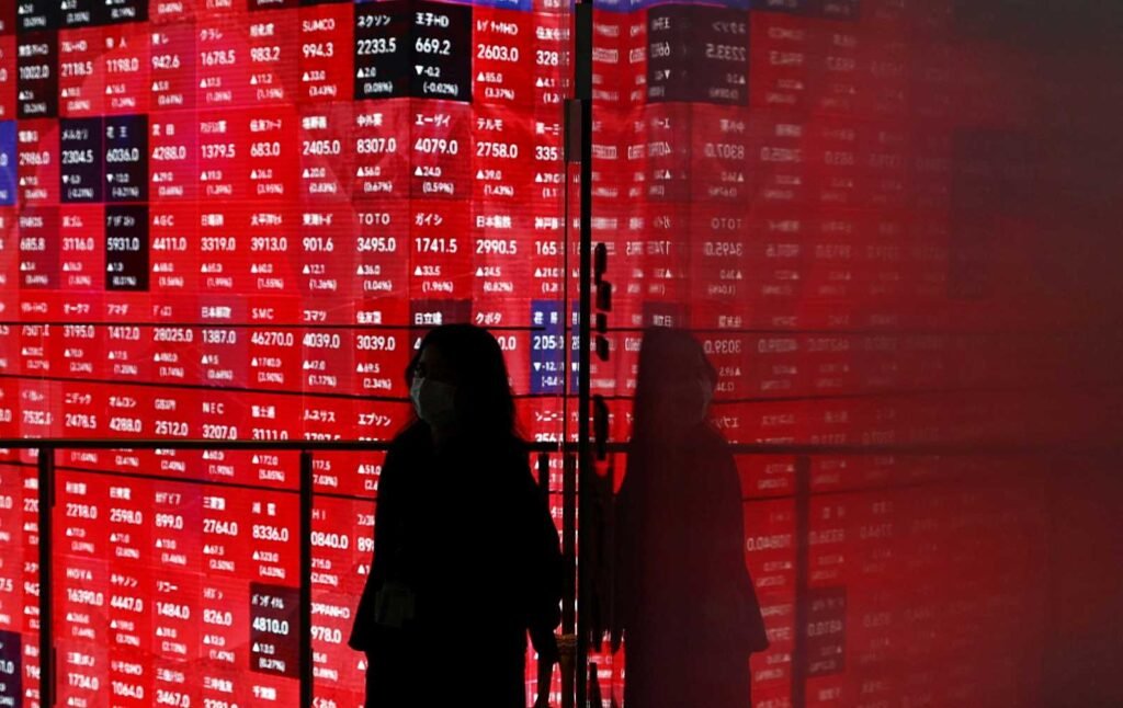 Seorang wanita berjalan di depan papan harga saham di dalam sebuah gedung di Tokyo, Jepang, 25 April 2025. REUTERS/Issei Kato