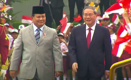Presiden Prabowo mengenakan jas abu abu dan peci hitam,dan PM China Li Qiang mengenakan jas hitam berdasi merah.