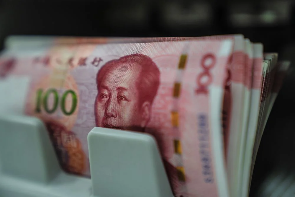 Uang kertas pecahan 100 yuan China dalam mesin penghitung mata uang. / Bloomberg-Lam Yik