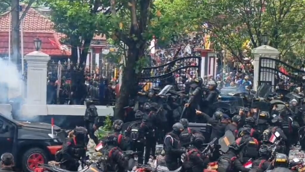 Petugas kepolisian berusaha menghadang dorongan Masa pendemo yang berusaha masuk sambil melempari dengan Batu dan botol mineral.