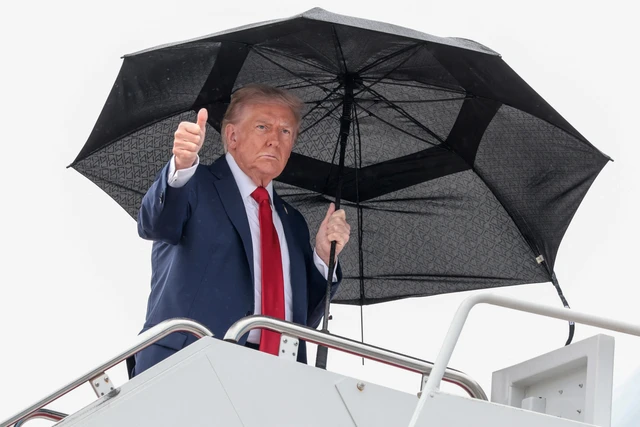 Presiden AS Donald Trump memegang payung sebelum menaiki Air Force One, saat berangkat ke Mesir di Pangkalan Gabungan Andrews, Maryland, AS, Minggu (12/10/2025). Foto: Evelyn Hockstein/REUTERS
