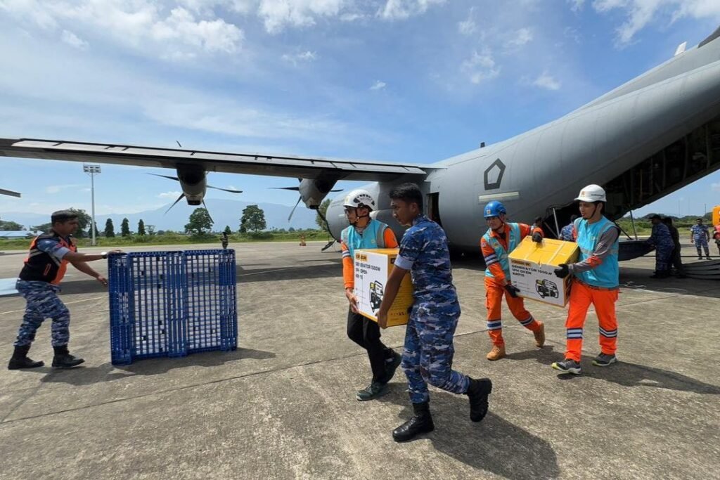 Tampak Personel PLN dan TNI Angkatan Udara bergotong royong memindahkan genset dan material tower darurat dari pesawat Hercules