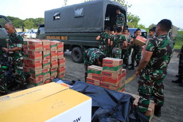 Prajurit TNI memuat logistik ke truk untuk didistribusikan ke daerah terdampak banjir bandang di Pangkalan Udara Sultan Iskandar Muda, Blang Bintang, Kabupaten Aceh Besar, Aceh, Jumat (28/11/2025). Foto: ANTARA FOTO/Ampelsa