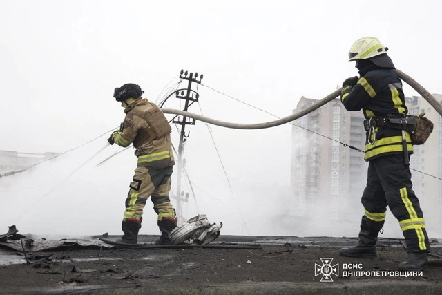 Petugas pemadam kebakaran berjalan di dekat puing-puing akibat serangan rudal Rusia ke Ukraina di Dnipro, Ukraina, Senin (1/12/2025). Foto: State Emergency Service of Ukraine/Handout via REUTERS
