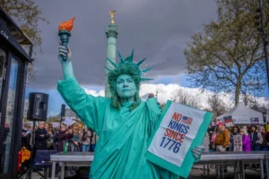 Seorang wanita yang berpakaian seperti Patung Liberty ikut serta dalam protes "Tidak Ada Raja" di Paris, Prancis, Sabtu, 28 Maret 2026. Foto: AP Photo/Aurelien Morissard