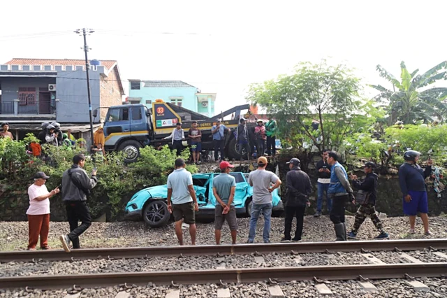 Warga mengamati kondisi taksi listrik yang rusak usai mengalami kecelakaan dengan KRL Commuter Line di Bekasi Timur, Bekasi, Jawa Barat, Selasa (28/4/2026). Foto: Iqbal Firdaus/kumparan