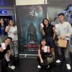 Para diaspora Indonesia yang berfoto menunjukkan tiketnya di depan poster The Rope Curse 4: Kuntilanak sebelum film dimulai. (Sumber Foto : CNA, 23 Agustus 2026).