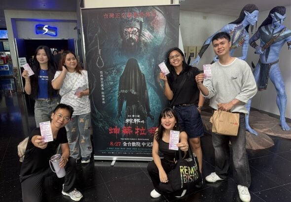 Para diaspora Indonesia yang berfoto menunjukkan tiketnya di depan poster The Rope Curse 4: Kuntilanak sebelum film dimulai. (Sumber Foto : CNA, 23 Agustus 2026).