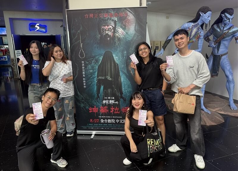 Para diaspora Indonesia yang berfoto menunjukkan tiketnya di depan poster The Rope Curse 4: Kuntilanak sebelum film dimulai. (Sumber Foto : CNA, 23 Agustus 2026).